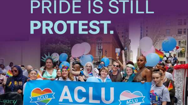 Philadelphia Pride attendees carry ACLU of PA banner to celebrate LGBTQ rights.