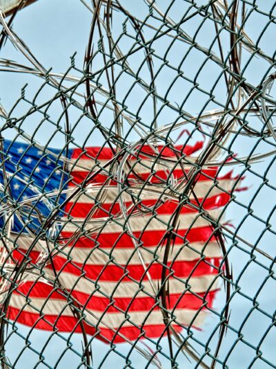 American flag in background; barbed wire in foreground