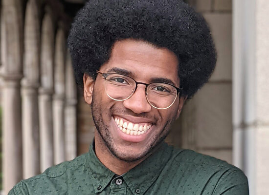 Solomon Worlds headshot. A smiling Black man wearing a green collard shirt.
