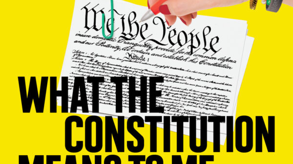 A hand signing on the constitution on a yellow background with the title of the play