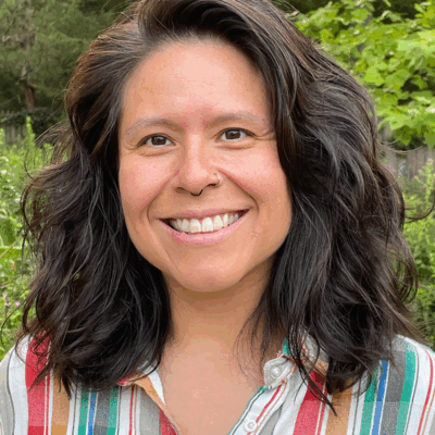 A picture of Veronica Miller smiling with medium length brown hair and a stripped button down shirt