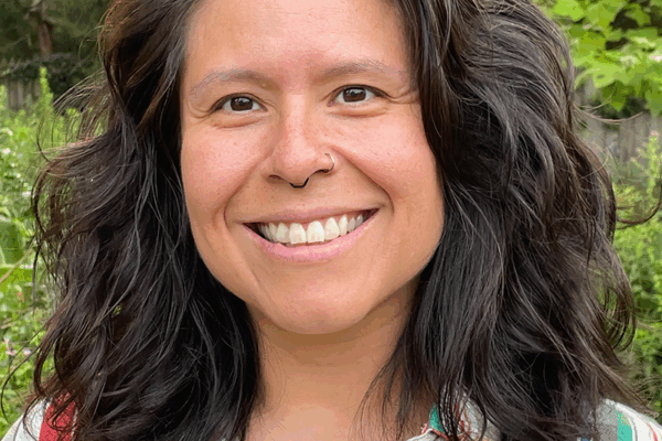 A picture of Veronica Miller smiling with medium length brown hair and a stripped button down shirt