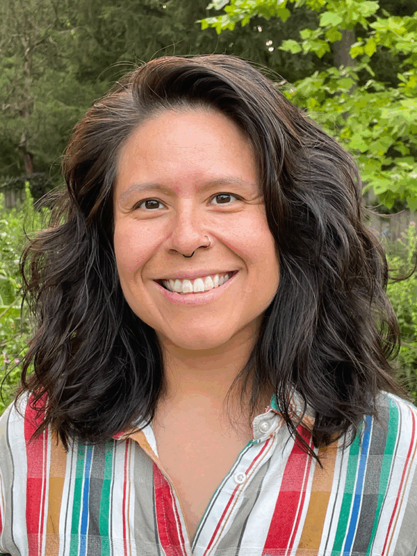 A picture of Veronica Miller smiling with medium length brown hair and a stripped button down shirt