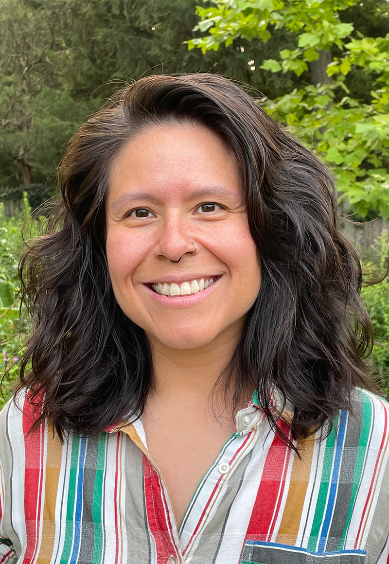 A picture of Veronica Miller smiling with medium length brown hair and a stripped button down shirt