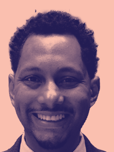 A picture of Mike Lee on a pink background smiling in navy suit and white button down