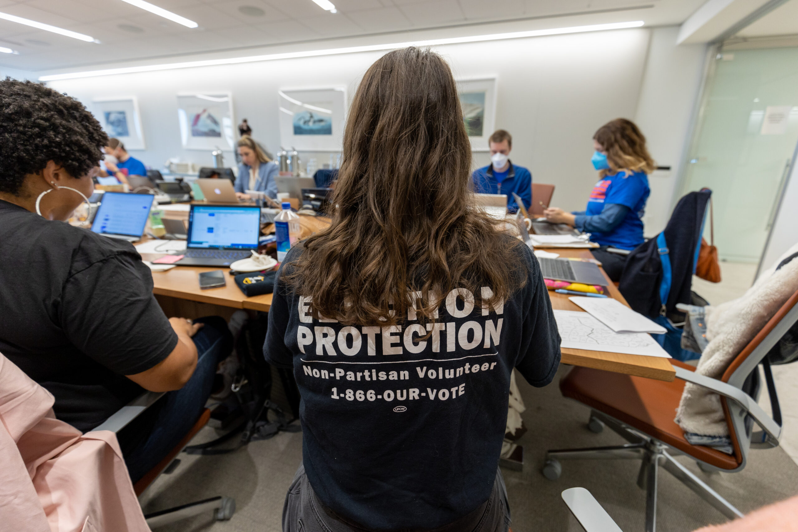 A person with long hair with a black Election Protection shirt