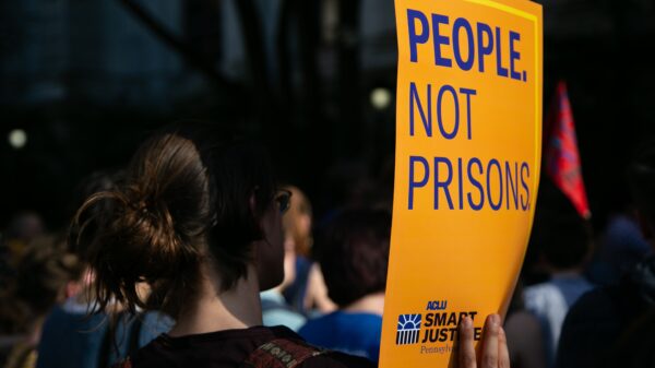woman holding sign that says "People Not Prisons"