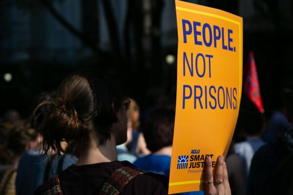 woman holding sign that says "People Not Prisons"