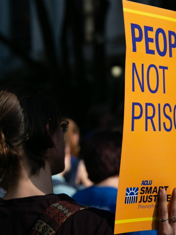 woman holding sign that says "People Not Prisons"