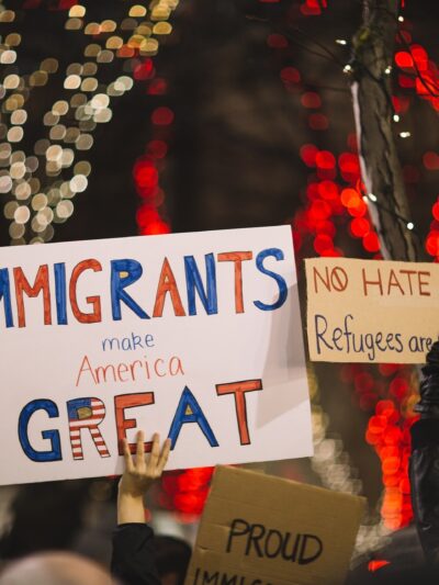protest signs reading 'Immigrants make America great' and 'no hate, no fear, refugees are welcome here'