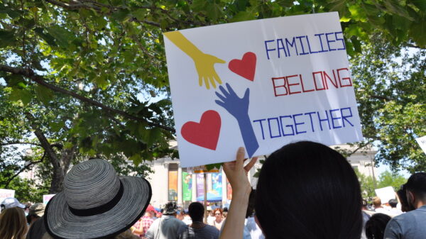 woman holding a sign that says "Families Belong Together"