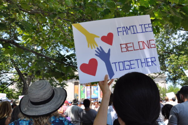 woman holding a sign that says "Families Belong Together"
