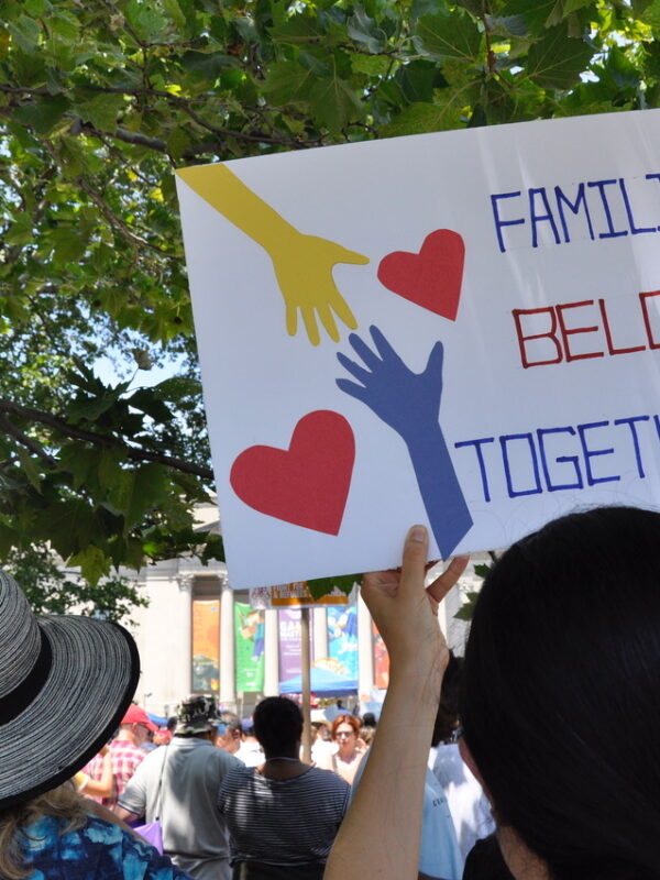 woman holding a sign that says "Families Belong Together"