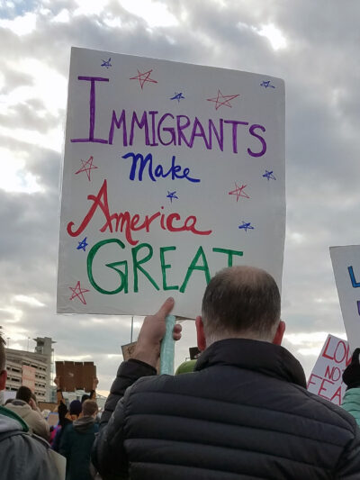 man holding sign that reads "Immigrants Make America Great"