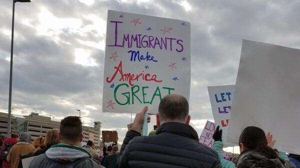 man holding sign that reads "Immigrants Make America Great"