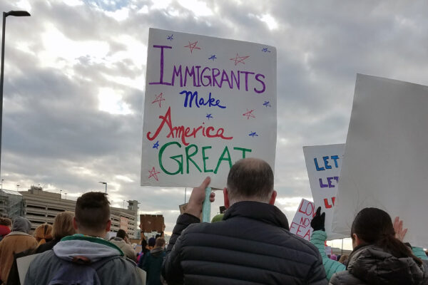 man holding sign that reads "Immigrants Make America Great"