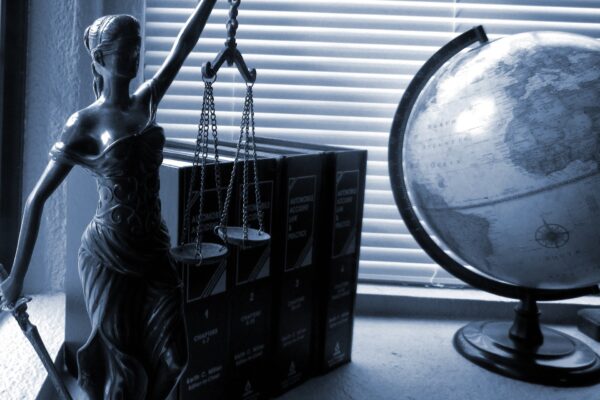 statue of lady justice, a set of books, and a globe sitting on a desk by a window