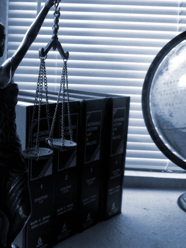 statue of lady justice, a set of books, and a globe sitting on a desk by a window