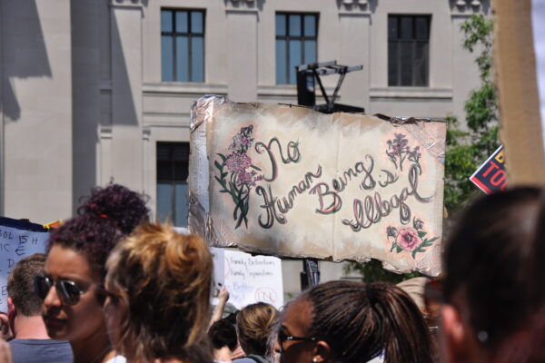 crowd of people and sign that reads 'No Human Being is Illegal'
