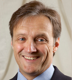A picture of Vic Walczak smiling in a headshot in a navy suit