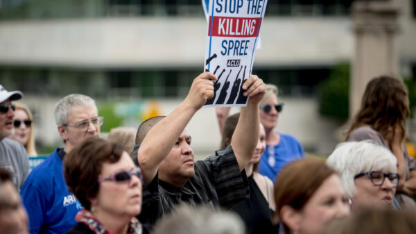 A person holding up a sign that says "Stop the killing spree".