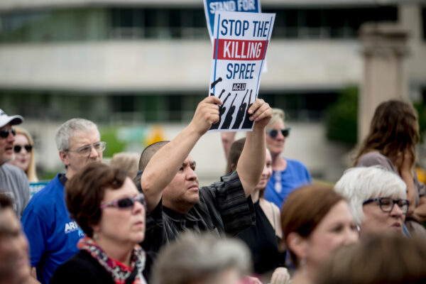 A person holding up a sign that says "Stop the killing spree".