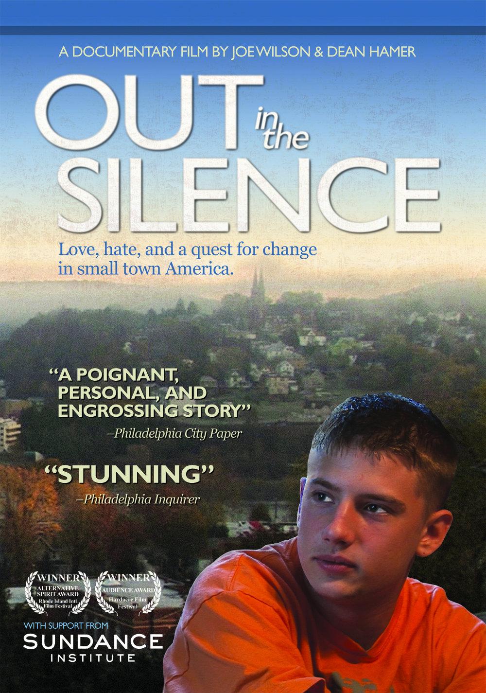 A boy in an orange shirt looking out in the distance behind the backdrop of a Pennsylvania town