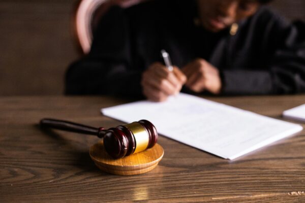 A judge writing on a piece of paper with a gavel in the foreground