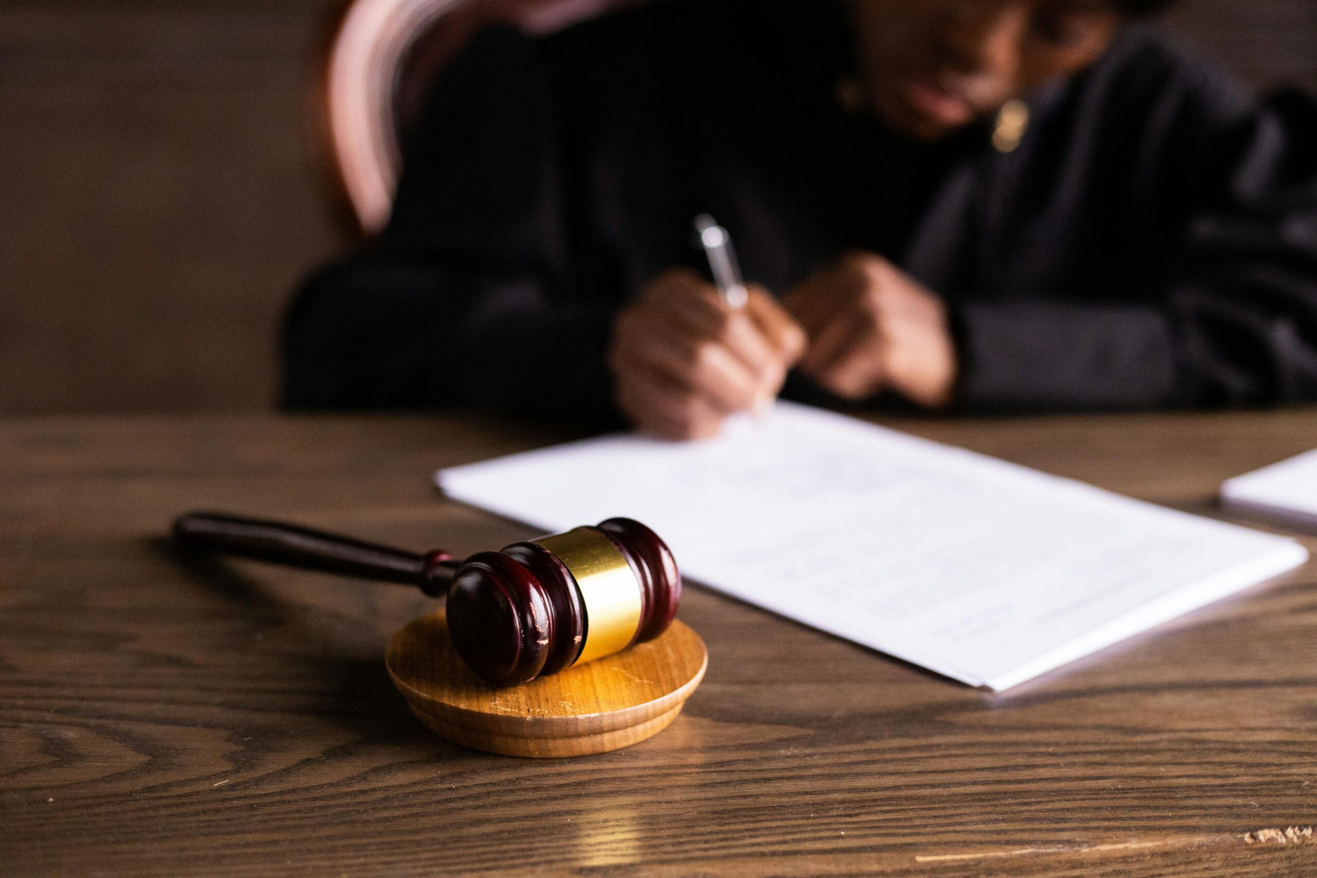 A judge writing on a piece of paper with a gavel in the foreground