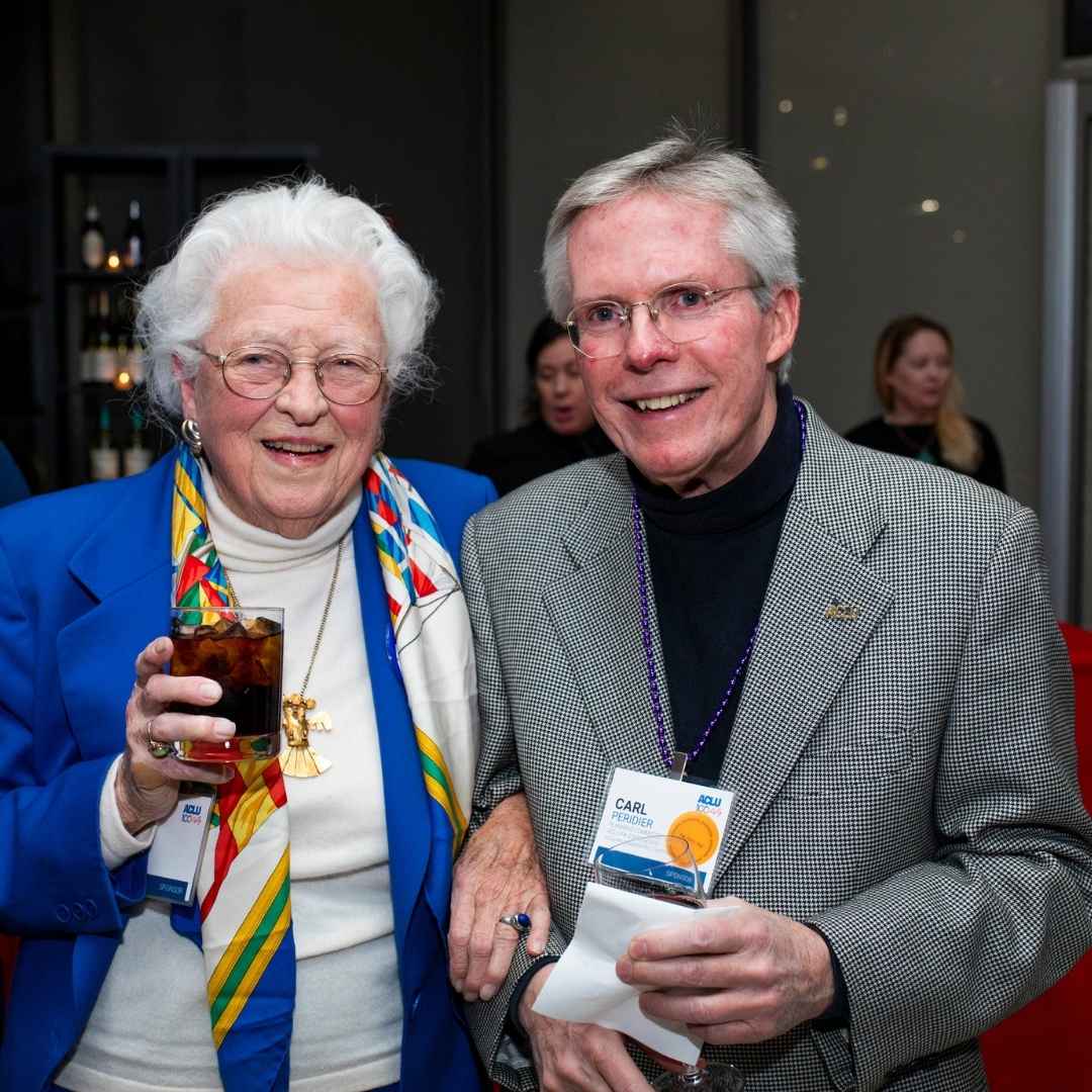 A photo of Carl standing with a woman who is wearing a blue blazer. They are both smiling.