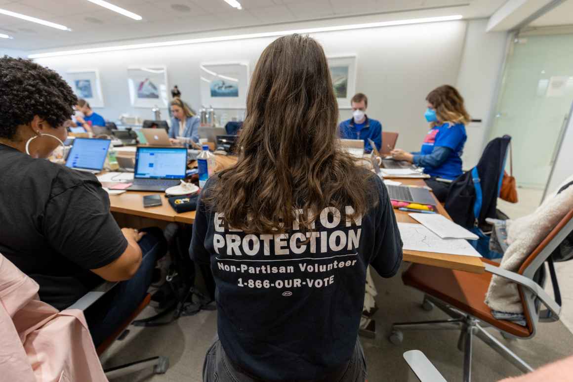 A person with long hair with a black Election Protection shirt 