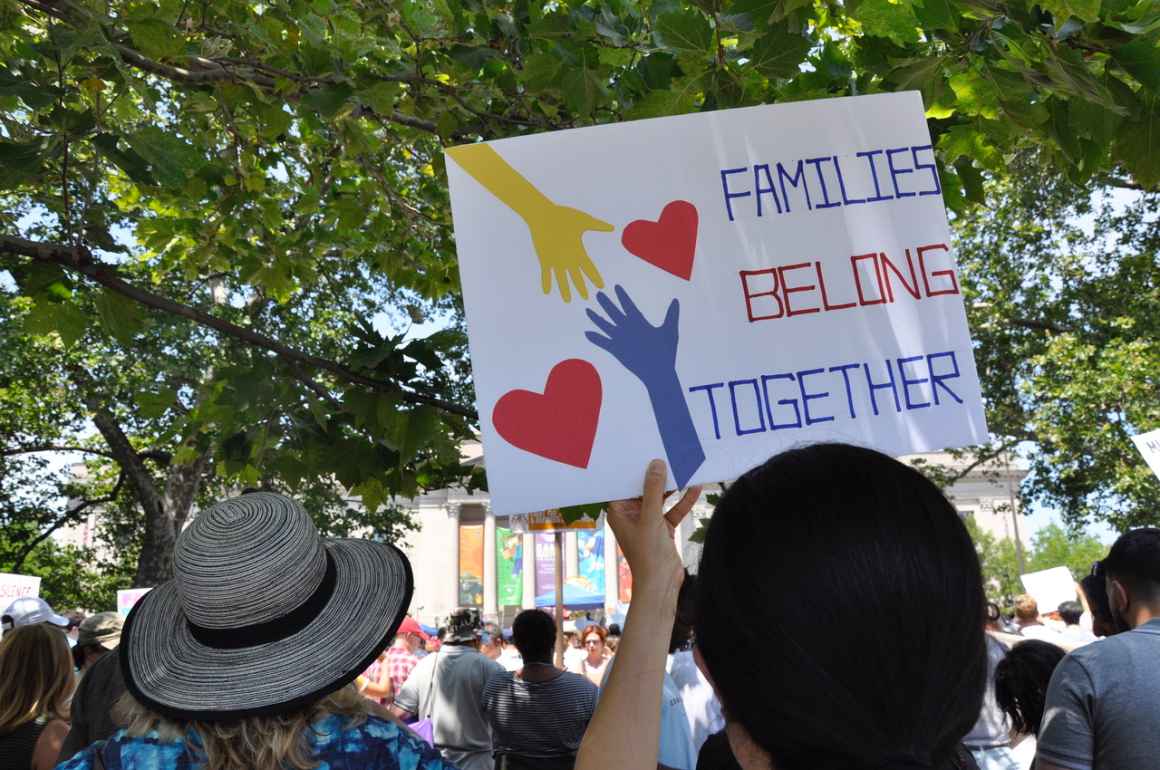 woman holding a sign that says "Families Belong Together"
