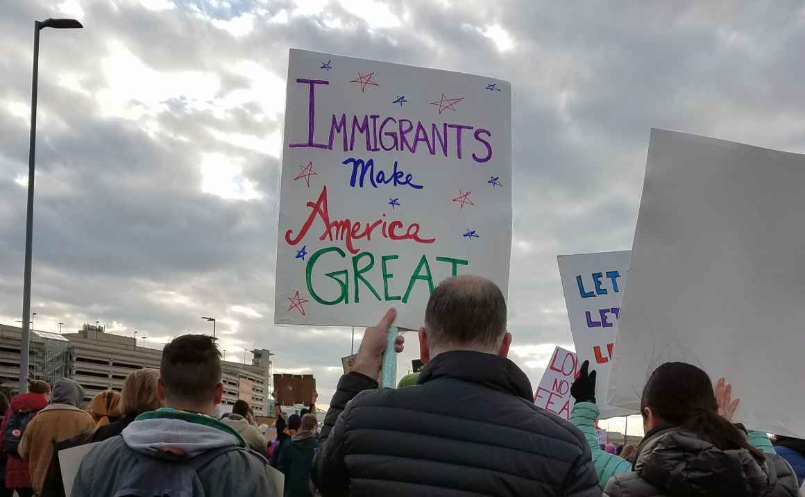 man holding sign that reads "Immigrants Make America Great"