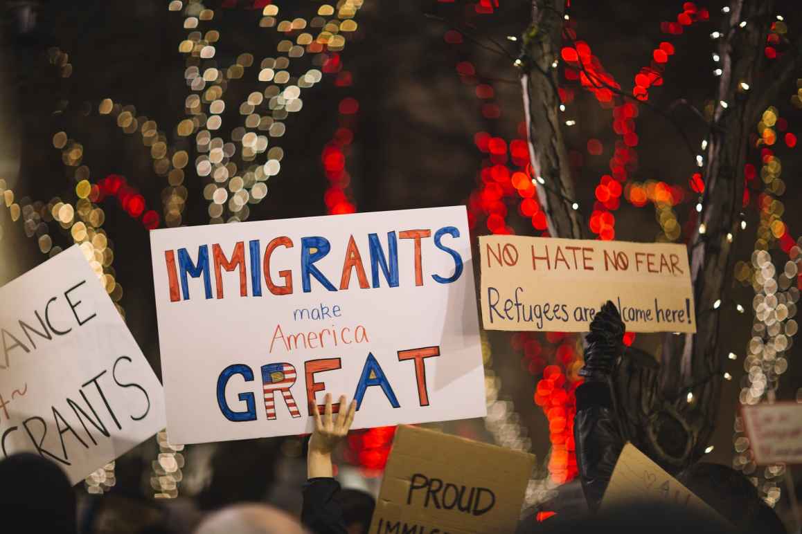 protest signs reading 'Immigrants make America great' and 'no hate, no fear, refugees are welcome here'