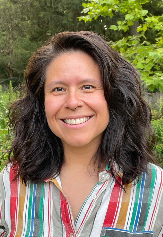 A picture of Veronica Miller smiling with medium length brown hair and a stripped button down shirt 