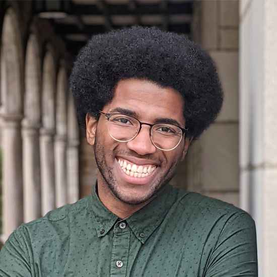 Solomon Worlds headshot. A smiling Black man wearing a green collard shirt.