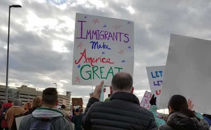 man holding sign that reads "Immigrants Make America Great"