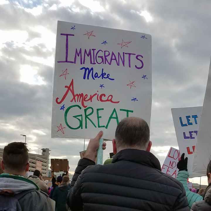 man holding sign that reads "Immigrants Make America Great"